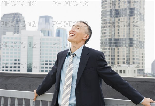 Happy businessman standing outdoors with eyes closed. Photo : Jamie Grill