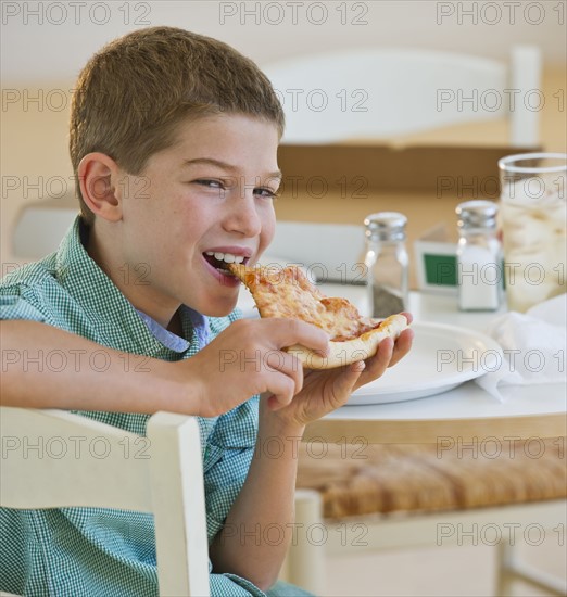 Boy (10-11) eating pizza. Photo : Daniel Grill