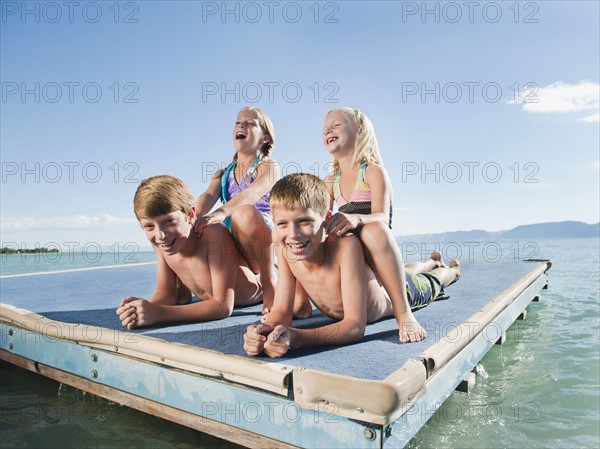 Kids (6-7,8-9,10-11,12-13) playing on raft on lake.