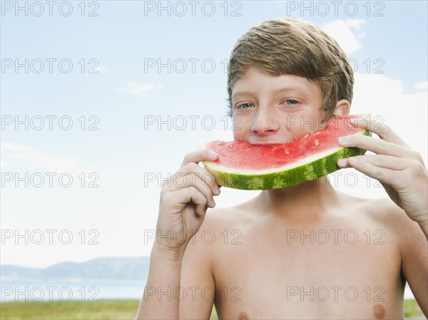 Boy (12-13) eating watermelon.