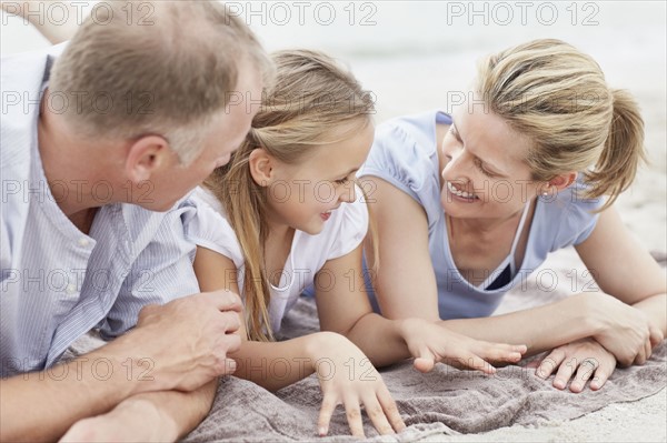 Girl (10-11) playing on beach with parents. Photo : Momentimages