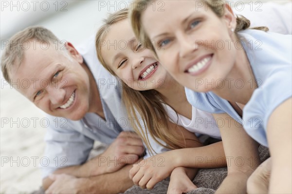 Girl (10-11) playing on beach with parents. Photo : Momentimages