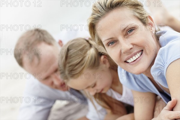 Girl (10-11) playing on beach with parents. Photo : Momentimages