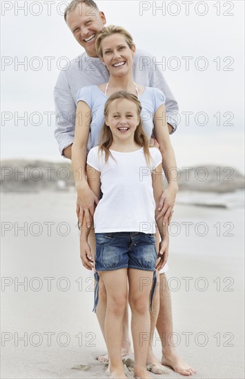 Girl (10-11) playing on beach with parents. Photo : Momentimages