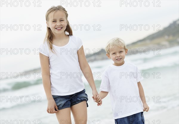 Girl (10-11) and boy (4-5) on beach. Photo : Momentimages