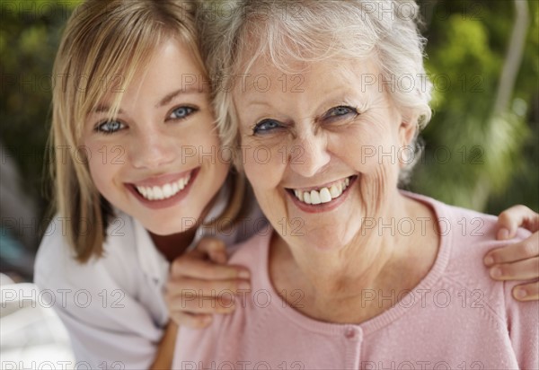 Daughter with mother looking at camera and smiling. Photo : Momentimages