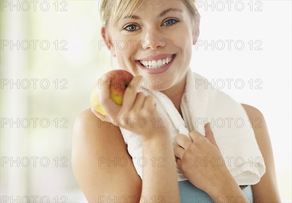 Portrait of young blonde woman holding apple. Photo : Momentimages