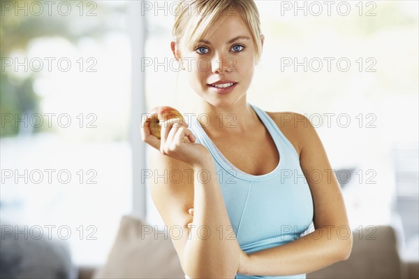 Portrait of young blonde woman holding apple. Photo : Momentimages