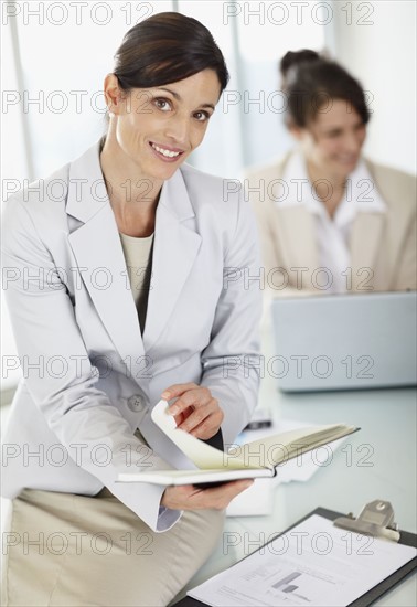 Two businesswomen working in office. Photo : Momentimages