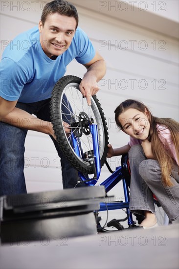 Father with daughter (10-11) fixing bike. Photo : Momentimages