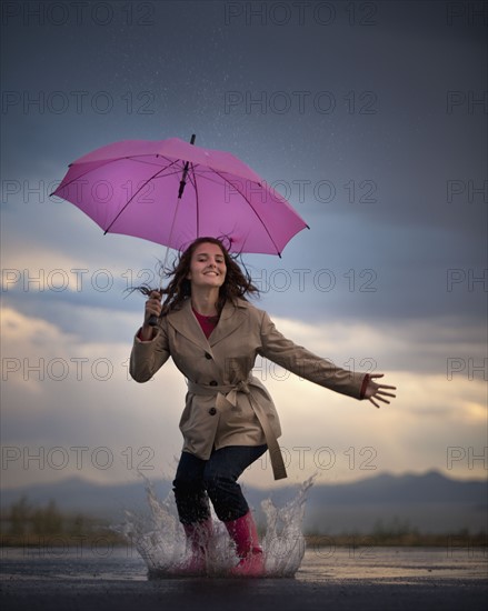 Young woman with umbrella under overcast sky. Photo : Mike Kemp