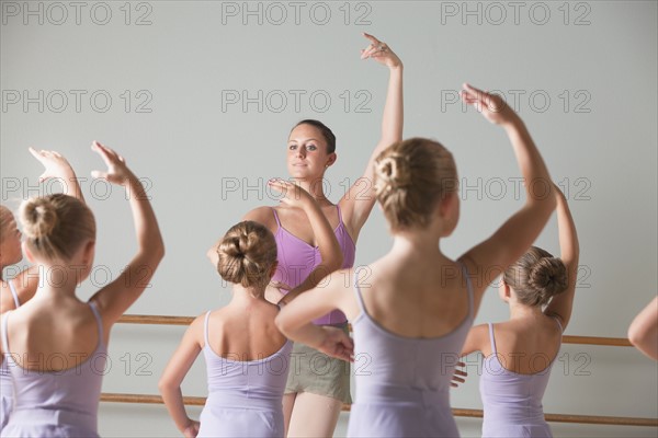 Female instructor training ballet dancers (6-8) in dance studio. Photo : Mike Kemp