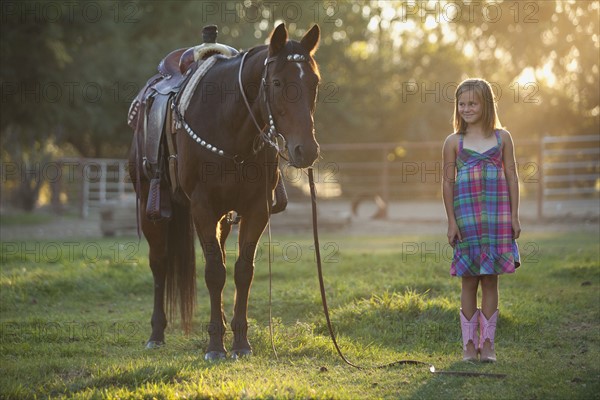 Girl (8-9) standing with horse in paddock. Photo : Mike Kemp