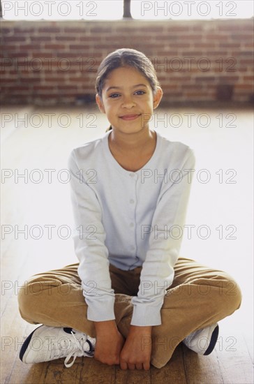 Cute girl sitting cross legged on floor. Photo : Fisher Litwin