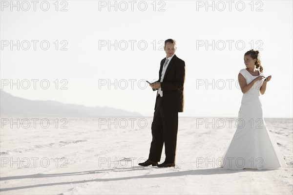 Bride and groom texting in desert. Photo : FBP