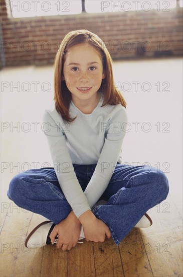Cute young girl sitting cross legged. Photo : Fisher Litwin