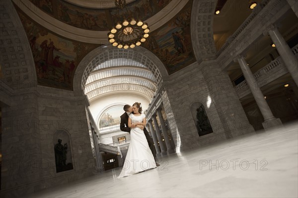 Bride and groom embracing under arch. Photo : FBP