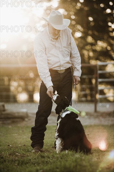 Cowboy feeding dog on ranch. Photo : Mike Kemp