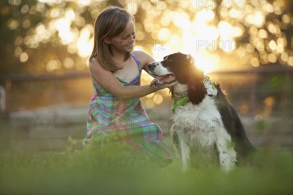 Girl (8-9) stroking dog in field. Photo : Mike Kemp