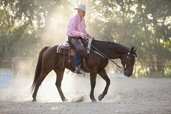 Senior man horseback riding in ranch. Photo : Mike Kemp