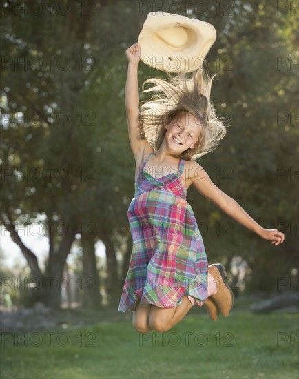 Portrait of smiling cowgirl (8-9) jumping. Photo : Mike Kemp