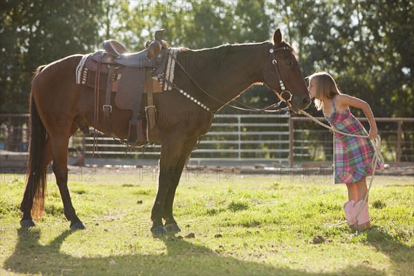 Cowgirl (8-9) kissing horse in ranch. Photo : Mike Kemp