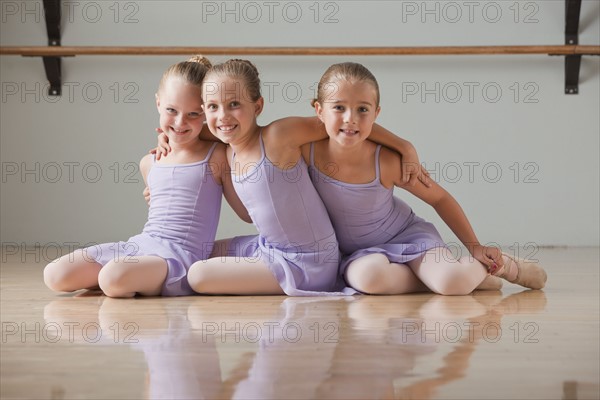 Portrait of female ballet dancers (6-7) embracing in dance studio. Photo : Mike Kemp