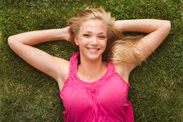 Young girl (16-17) lying on grass. Photo : Mike Kemp