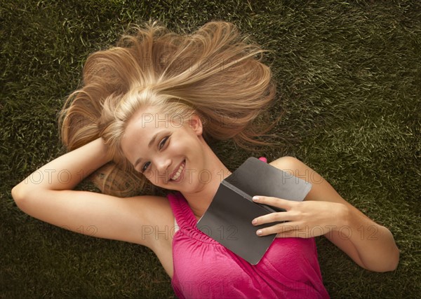 Young girl (16-17) lying on grass. Photo : Mike Kemp