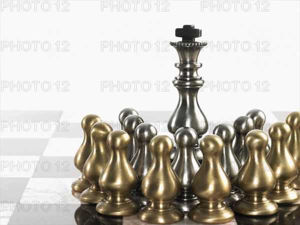 King surrounded by pawn chess pieces. Photo : David Arky