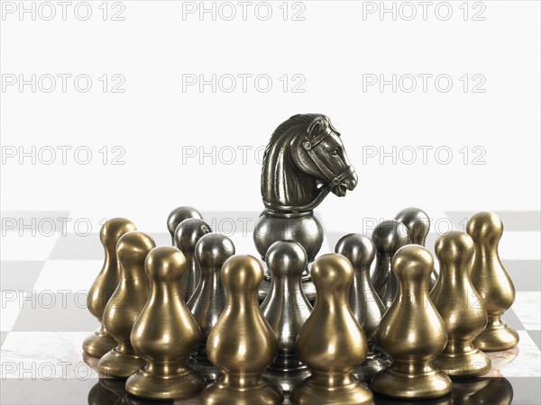 Knight surrounded by pawn chess pieces. Photo : David Arky