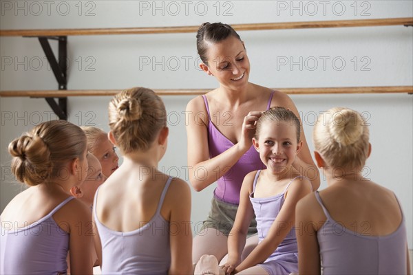 Female instructor training ballet dancers (6-8) in dance studio. Photo : Mike Kemp