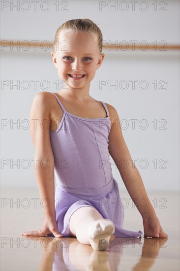 Portrait of ballet dancer (6-7) performing splits in dance studio. Photo : Mike Kemp