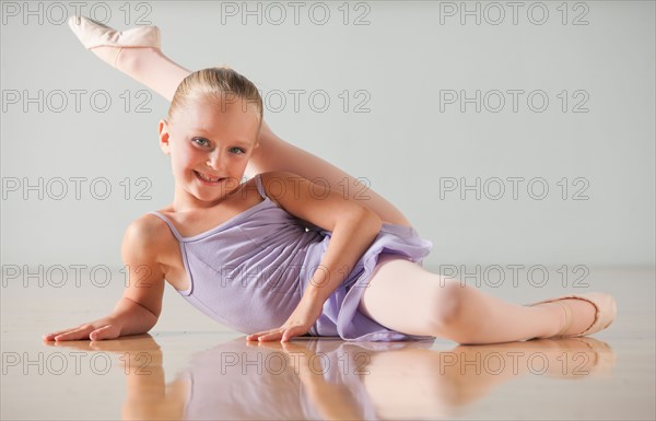 Portrait of female ballet dancer (6-7) stretching in dance studio. Photo : Mike Kemp
