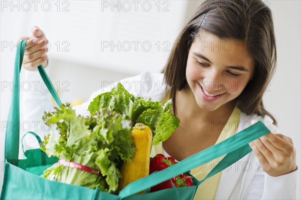 Girl (12-13) holding groceries .