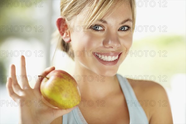 Portrait of young blonde woman holding apple. Photo : Momentimages