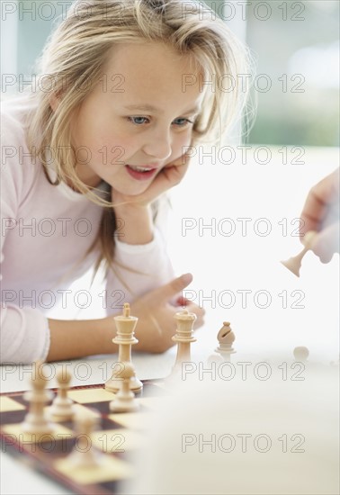 Granddaughter (10-11) playing chess with grandfather. Photo : Momentimages