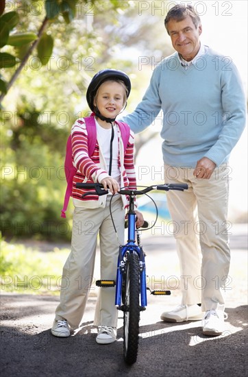 Portrait of grandfather and granddaughter (10-11) with bike. Photo : Momentimages