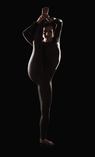 Female contortionist on black background. Photo : Mike Kemp