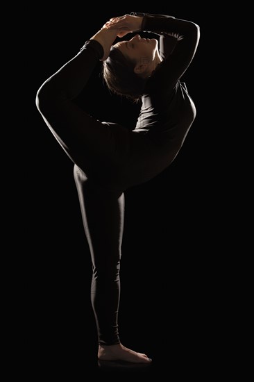 Female contortionist on black background. Photo : Mike Kemp