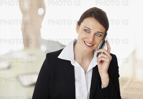 Smiling businesswoman using mobile phone. Photo : Momentimages