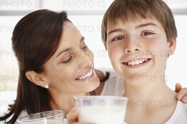 Portrait of smiling mother and son (12-13)  with glasses of milk. Photo : Momentimages