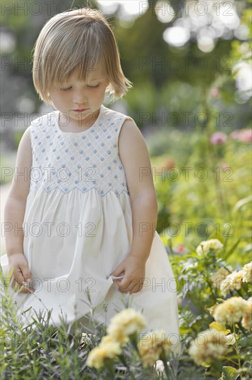 Girl (2-3) by flowers in garden. Photo : FBP