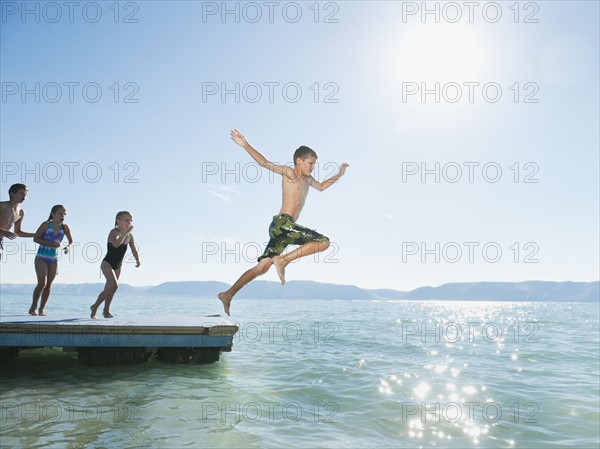 Kids (6-7,8-9,10-11,12-13) playing on raft on lake.