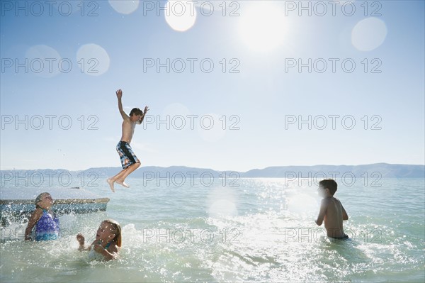 Kids (6-7,8-9,10-11,12-13) playing on raft on lake.