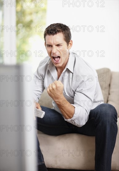 Excited man watching football match. Photo : Momentimages