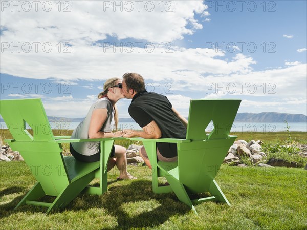 Young couple sitting on meadow and kissing.