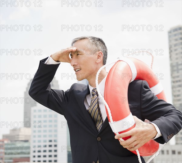 Businessman looking away and holding life belt. Photo : Jamie Grill
