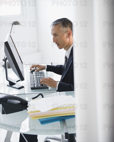 Businessman working on computer in office. Photo : Jamie Grill