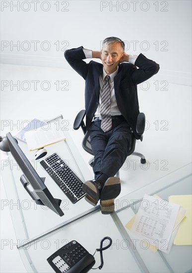Businessman with feet on desk smiling. Photo : Jamie Grill